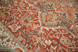 Distressed Heriz carpet detail with cherry red abrash, geometric motifs, and soft blue accents.