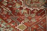 Distressed Heriz carpet detail: geometric vines, cherry red, dusty teal, and visible wear.