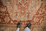Textural Heriz carpet showing varied red, dusty teal, and ivory patterns with abrashes.