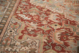 Distressed Heriz carpet's textured brick red field with geometric patterns and faded hues.