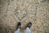 Textural view of a distressed Heriz carpet, showcasing geometric motifs in sand and pale blue.