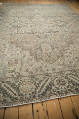 Distressed Heriz carpet corner featuring serrated leaf border and beige, charcoal geometric motifs.