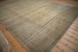Distressed Yezd carpet revealing worn pale gold, blue motifs and wide border.