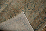 Distressed antique Persian Yezd carpet corner revealing faded florals, worn pile, and hand-knotted foundation.