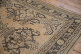 Distressed texture and geometric floral patterns on a vintage beige and dark brown Oushak carpet.