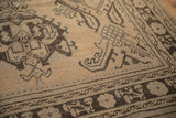 Distressed vintage Oushak rug detail with beige field and dark brown geometric floral border.
