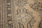 Distressed vintage Oushak rug border, featuring cream floral elements and dark chocolate geometric patterns.