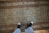 Distressed vintage Hamadan runner showing intricate Herati pattern in dusty teal, ivory, brown.