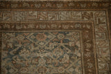 Distressed Hamadan rug corner with muted dusty teal, charcoal, and chocolate Herati pattern.