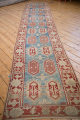 Distressed Oushak runner detail: cherry red cartouches, aquatic blue, and vine-floral border.