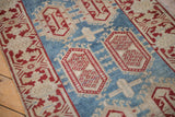 Distressed Oushak rug's aquatic blue field, cherry red cartouches, and beige vine border.