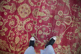 Low pile and visible knot heads on the raspberry magenta field of a distressed antique Yezd rug.