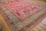 European-influenced floral border in dusty teal on a distressed raspberry-red antique Yezd carpet.