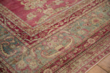 European-influenced floral sprays on the jade green and magenta corner of a distressed Yezd carpet.