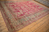 Angled perspective of the antique Yezd carpet's sprawling floral design and distressed raspberry pile.