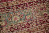 Bands of Persian floral motifs in raspberry red and dusty teal with even, time-softened wear.
