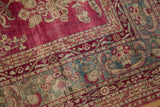 Abrashed raspberry magenta and jade green corner detail on a distressed antique Persian Yezd carpet.