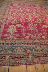 Abrashed raspberry field and dusty teal border of a distressed antique Persian Yezd carpet.