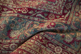 Softly draped antique Yezd carpet showing worn texture in raspberry, teal, and sand.