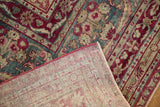 The hand-knotted foundation and raspberry floral pile seen on a folded corner of an antique Yezd rug.