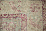 Detail of an antique Kerman corner with raspberry red spandrels and visible wear to the knot heads.