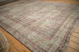 Distressed low-pile weave and raspberry floral spandrels on the corner of an antique Kerman carpet.