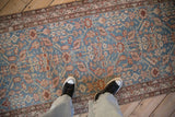 A view down the length of a distressed antique Malayer runner, showing its sky blue floral pattern and low pile.