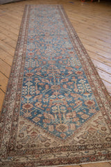 Angled view of a distressed Persian Malayer runner showing its full length and pattern.