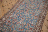 Angled view of an antique Malayer runner's interconnected blossom design on a sky blue field.