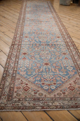 Long perspective view of a distressed antique Malayer runner showing its sky blue and terracotta pattern.