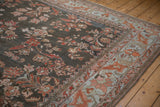 Distressed vintage Lilihan carpet corner, charcoal field, fluid border, cherry red blossoms.