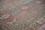 Distressed Bakhtiari carpet detail: faded garden motifs in ruby red, sky blue, and beige.