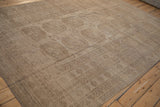 Distressed Ersari carpet corner with low pile, geometric borders, and camel sand colors.