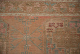 Geometric border and abrashed field of a vintage Ersari rug in faded rose and dusty blue.