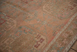 Worn texture of a vintage Ersari carpet showing a dusty blue geometric gul on a blush pink field.