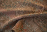 Soft, distressed texture of a vintage Ersari carpet in blush and dusty blue tones.