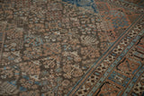 Distressed Persian Joshegan rug detail: brown field with blue willow motifs and orange border.