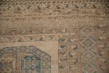 Distressed Ersari rug border in sand, beige, and dusty blue geometric patterns.