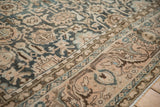 Distressed Malayer rug close-up showing dusty teal, coral, brown vine and palmette border.