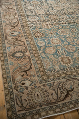 Distressed Malayer carpet corner with worn dusty teal floral field and fluid pale coral vine border.