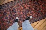 A look down at the traditional floral pattern of a vintage Lilihan runner in blush, blue, and olive.