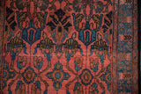 Plush hand-knotted pile showing sapphire blue and olive floral palmettes on a deep blush red field.