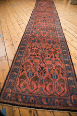 A vintage Persian runner's full length, showing repeating floral palmettes in blush and sapphire blue.