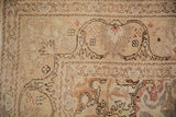 Distressed Kayseri rug corner shows faded sand, scalloped spandrel, and dragon arabesque border.