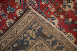 Folded corner of the vintage Kurdish Hamadan carpet showing its hand-knotted foundation and thick red pile.