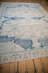Distressed blue lattice and geometric border patterns on ivory vintage Bakhtiari carpet corner.