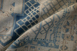 Distressed Bakhtiari carpet pile, featuring faded dusty blue lattice patterns on a sand background.