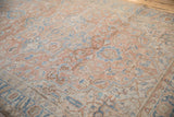 Serrated palmettes and vinery details on a distressed sandalwood and blue Heriz rug.