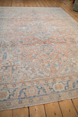 Angled view of a distressed Heriz carpet showing the soft, faded sandalwood and blue pile.