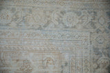Distressed Mahal carpet close-up: muted platinum, ivory, and dusty teal tones, showing aged pile texture.